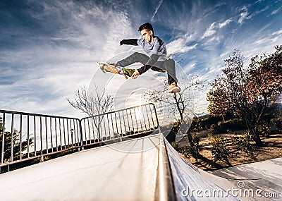 Young skater making a jump on Skatepark during sunset Stock Photo