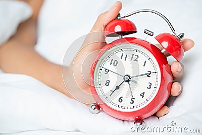 Young sleeping woman and alarm clock in bedroom Stock Photo