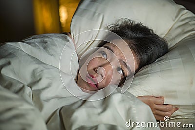 Young sleepless beautiful and scared Asian Japanese woman lying on bed awake at night suffering nightmare after watching zombie Stock Photo