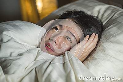 Young sleepless beautiful and scared Asian Korean woman lying on bed awake at night suffering nightmare after watching zombie Stock Photo