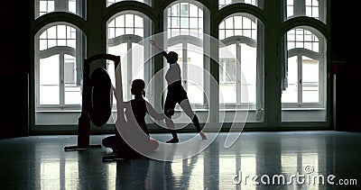 Young slender blonde girl is in a large Studio with large Windows, she sits at the Gong and beats it, creating sound Stock Photo