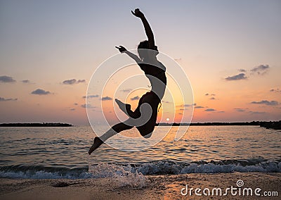 Young slender woman enthusiastically jumps up and has fun at sunset on the beach by the sea Stock Photo