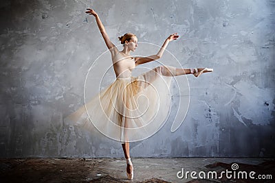 Young ballerina in a golden colored dancing costume is posing in a loft studio Stock Photo