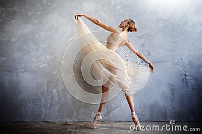 Young ballerina in a golden colored dancing costume is posing in a loft studio Stock Photo