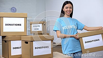 Young smiling activist holding donation box, volunteering center, philanthropy Stock Photo