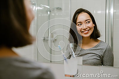 Young smiling asian girl standing in front of a mirror Stock Photo