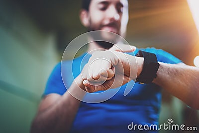 Young smiling athlete checking burned calories on electronic smart watch application after good indoor workout session Stock Photo