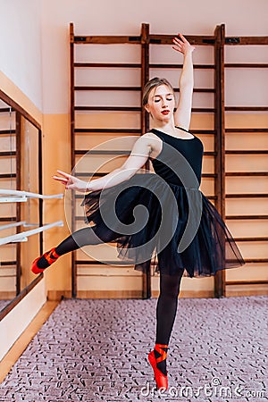 Young Smiling Ballerina Wearing black Tutu Doing exercise in training hall Stock Photo