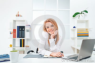 Young smiling business woman in white modern office. Beauty secretary. Beautiful young woman working with laptop in Stock Photo