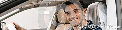 Young smiling car mechanic testing car while working in garage Stock Photo