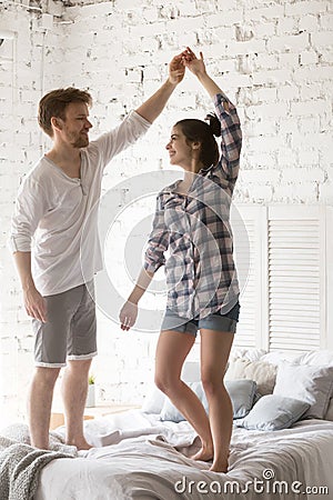 Young smiling couple in love dancing at bed together in bedroom Stock Photo