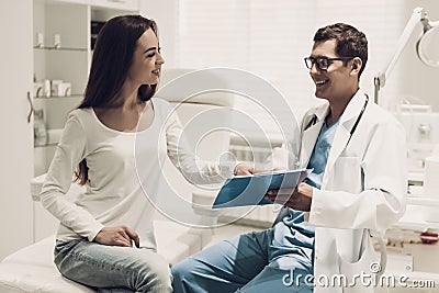 Young Doctor Consulting Beautiful Woman in Clinic. Stock Photo