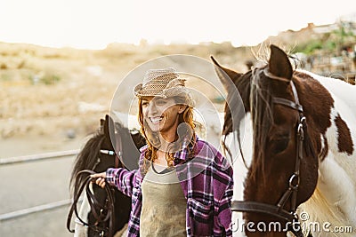 Young smiling farmer taking care of horses inside ranch Stock Photo