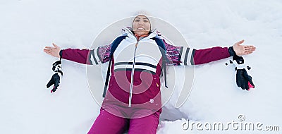 Young smiling female liying on the white snow wide opened her arms Stock Photo