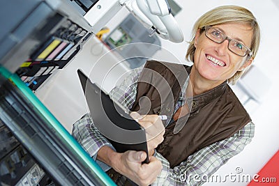 Young smiling female technician in overalls holding clipboard Stock Photo