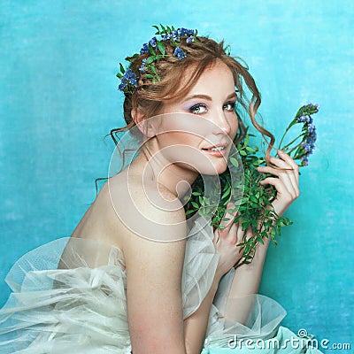Young smiling girl with blue flowers on light blue background. Spring beauty portrait Stock Photo