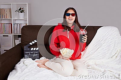 A young smiling girl with 3d glasses is watching a movie at home. Stock Photo