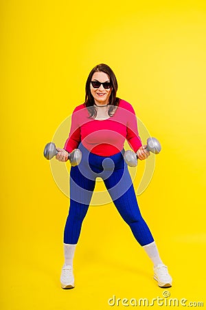 Young smiling happy chubby overweight plus size big fat fit woman warm up training hold dumbbells Stock Photo