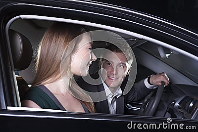 Young smiling, happy, couple sitting in their car and arriving at a red carpet event at night in Beijing Stock Photo