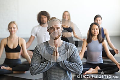 Young smiling male yoga instructor and group in lotus pose Stock Photo