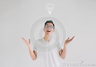 Young smiling man having a good idea. Portrait of an excited nerd with glasses and a white T-shirt pointing finger up at Stock Photo