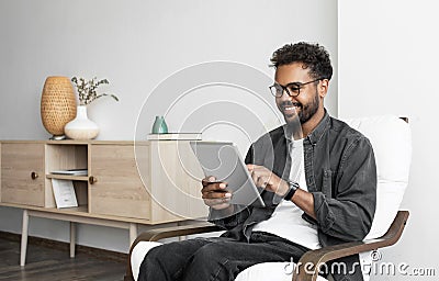 Young smiling man using digital tablet computer at home, Leisure, relaxation, online learning, web chat concepts Stock Photo