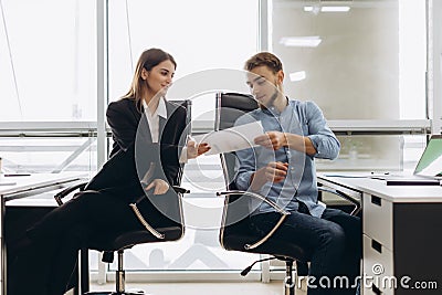 Young smiling personal assistant giving document to office worker in his office, female accountant reporting great work to ceo, Stock Photo