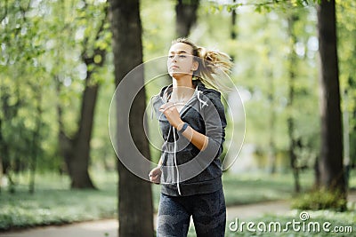 Young smiling sporty woman running in park in the morning. Fitness girl jogging in park Stock Photo