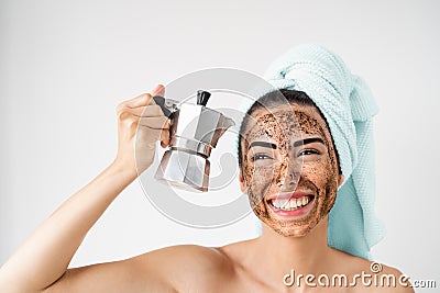 Young smiling woman applying coffee scrub mask on face - Happy girl having healthy skin care spa day at home Stock Photo