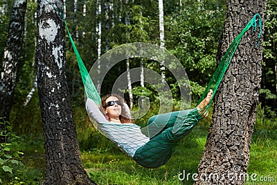 Young smiling woman in dark sunglasses lies in hammock Stock Photo