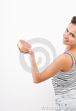 Young smiling woman holds out a grapefruit Stock Photo