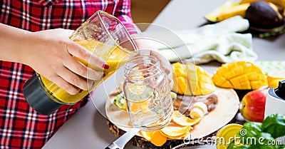 Young smiling woman making smoothie with fresh greens in the blender in kitchen at home Stock Photo