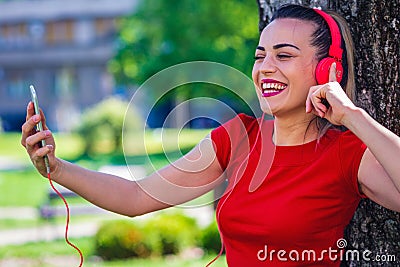 Young smiling woman making video call via smartphone and headphones. Stock Photo