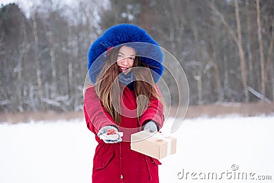 Young smiling woman in red givind gift boxes outdoors Stock Photo