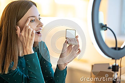 Young smiling woman shpowing new eyeshadows to onine audience Stock Photo