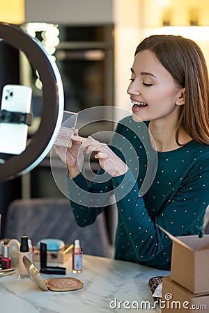 Young smiling woman shpowing new eyeshadows to onine audience Stock Photo