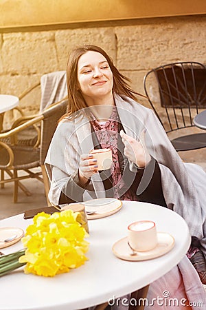 Cheerful young woman in a street cafe drinking coffee Stock Photo