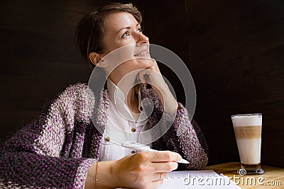 Young smiling woman thinking with pen and open notebook. Thoughtful girl portrait. Journalist and writer concept. Business lifesty Stock Photo