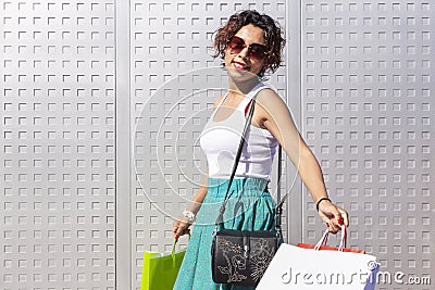 Young, smiling woman walking with her shopping bags outside a shopping centre Stock Photo