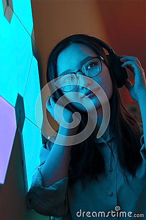 Smiling woman with headphones in violet blue neon light listen to music, nightclub futuristic neon of electronic sound Stock Photo