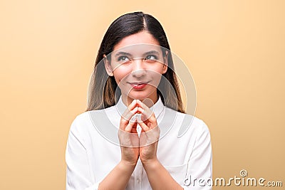 Young sneaky woman in white shirt, scheming something new for her business against orange background Stock Photo