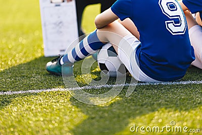 Young Soccer Player During Training Session. Children Sitting on Green Football Venue. Soccer Coaching Background Stock Photo