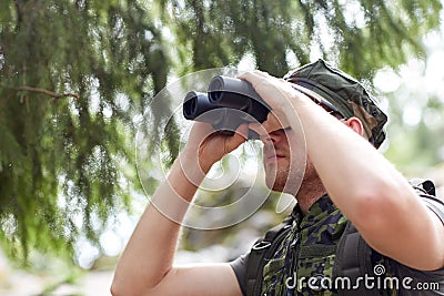 Young soldier or hunter with binocular in forest Stock Photo