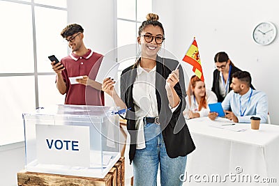 Young spanish voter woman smiling happy holding spain flag at vote center Stock Photo