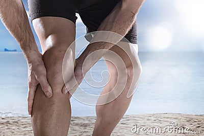 Young sport man with athletic legs holding knee in pain suffering muscle injury running Stock Photo