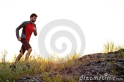 Young Sportsman Running on the Rocky Mountain Trail at Sunset. Active Lifestyle Stock Photo