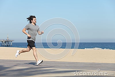 Young sportsman running on the seafront of the beach Stock Photo