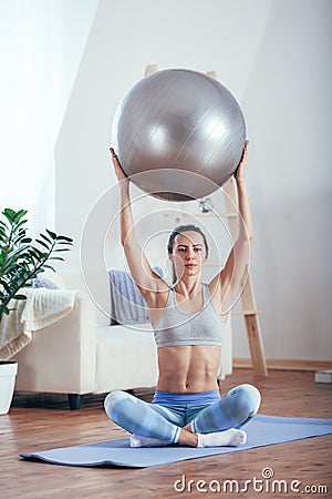 Young sportswoman doing exercises with ball on a mat at home Stock Photo