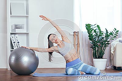 Young sportswoman doing exercises with ball on a mat at home Stock Photo