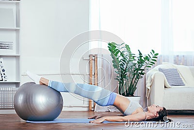 Young sportswoman doing exercises with ball on a mat at home Stock Photo